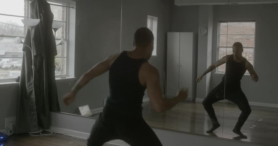 A man is dancing in front of a mirror