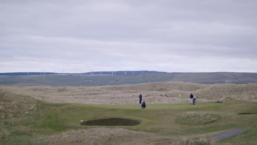 Friends play golf together at course near mountains on an overcast day