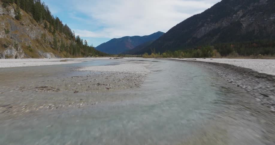 Aerial of a river with clear waters between forest and mountains