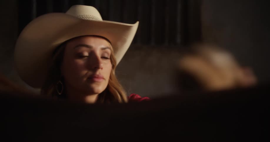 Woman with a hat grooming her horse at a ranch