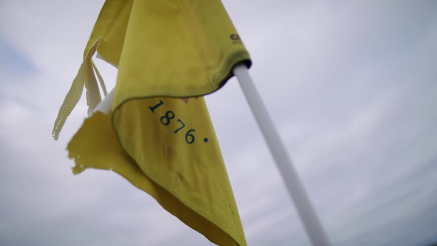 Yellow golf flag against a cloudy sky