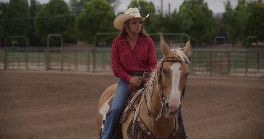 A blonde woman in a cowboy hat is on top of a horse