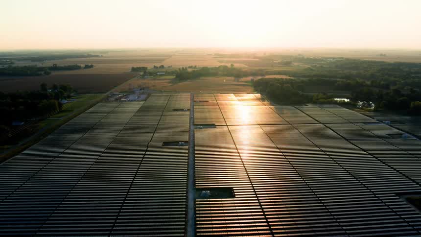 Aerial panorama of a solar panel station in a natural environment with morning sunlight reflection