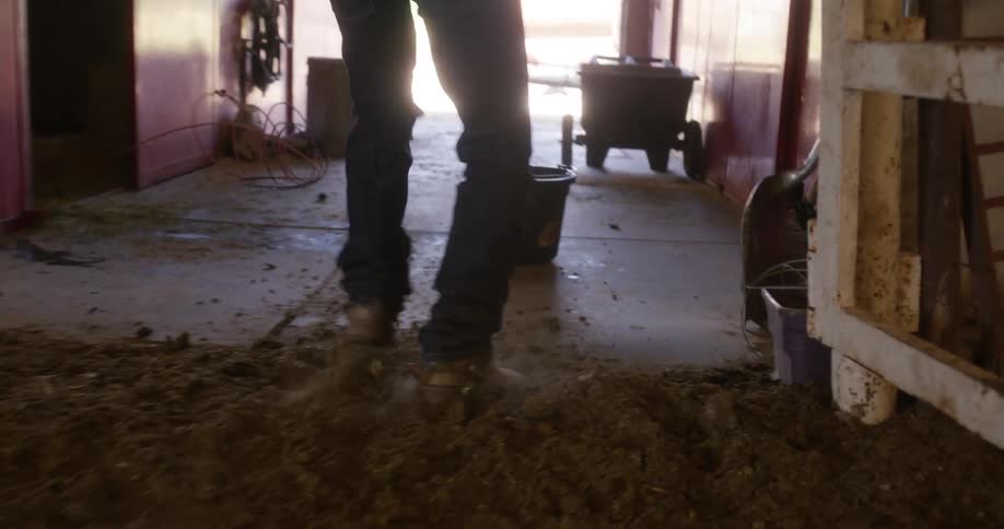 Angry cowboy walks out of a stable trashing the place