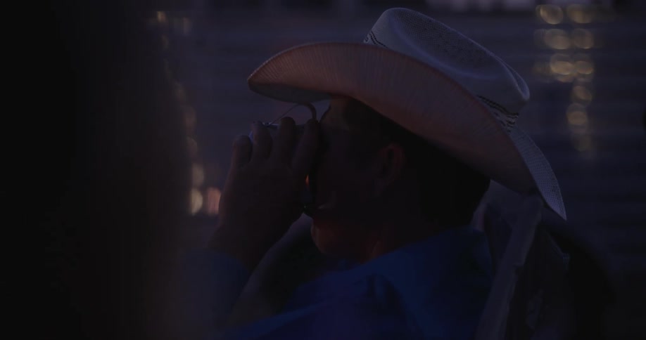 Cowboy sitting and drinking a beverage from a cup
