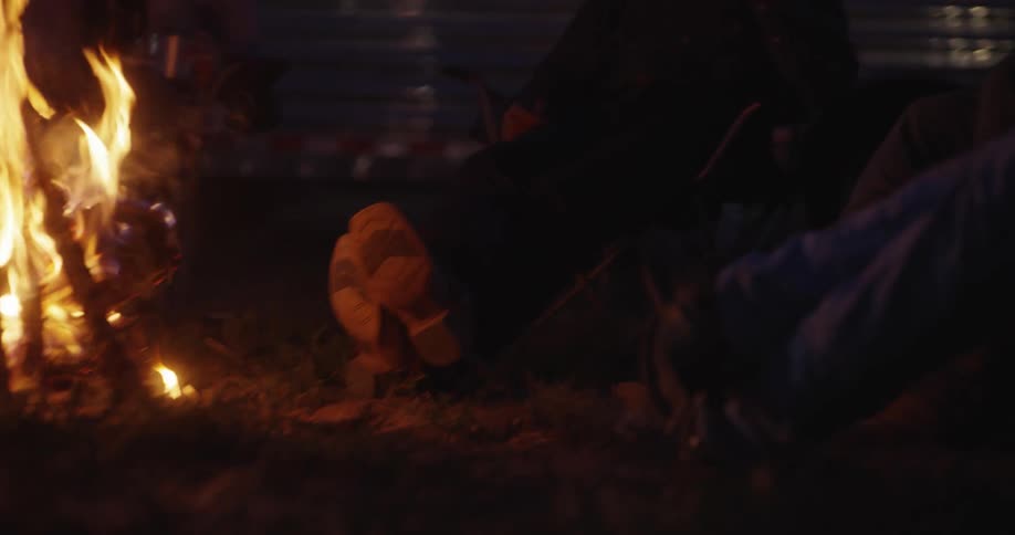 A couple of cowboys relaxing in front of a campfire