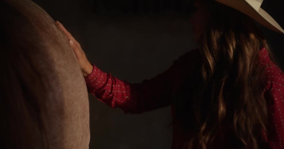 Portrait of a woman petting her horse inside the ranch