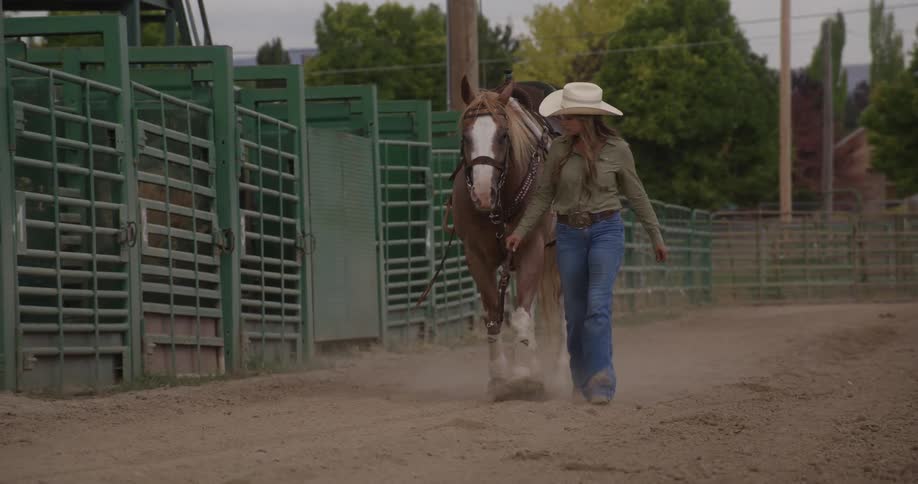 Woman walking alongside her horse in a rodeo field