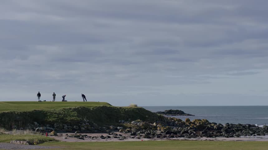 Men playing golf in a seaside location