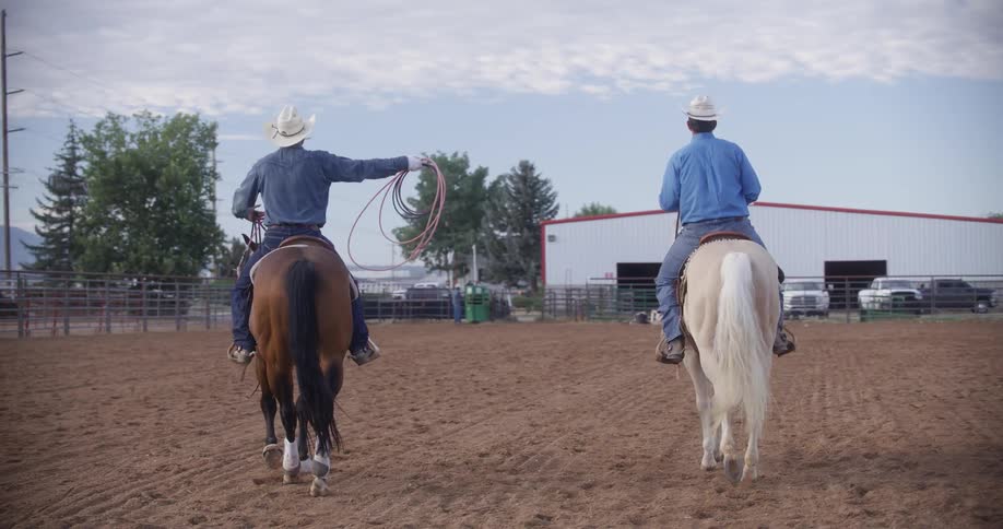 Two cowboys riding horses on a ranch