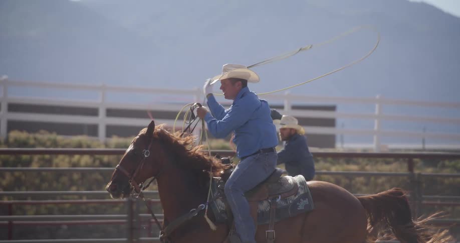 Two men in a fenced area with lassos