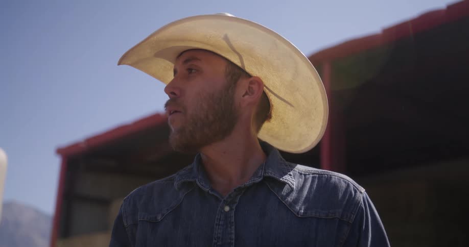 A cowboy wipes his face outside