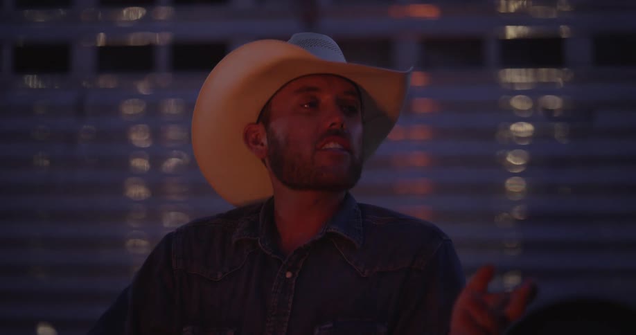 Cowboy talks while sitting at a campfire