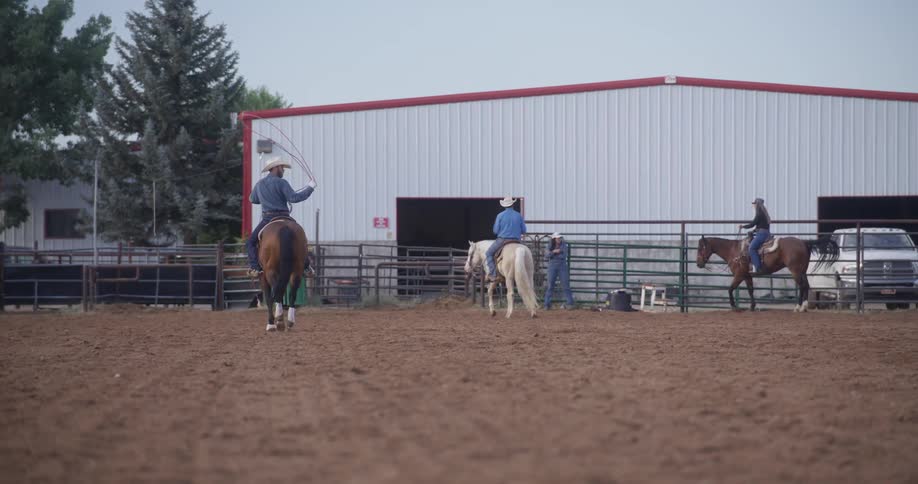 Three men riding horses on a dirt ranch