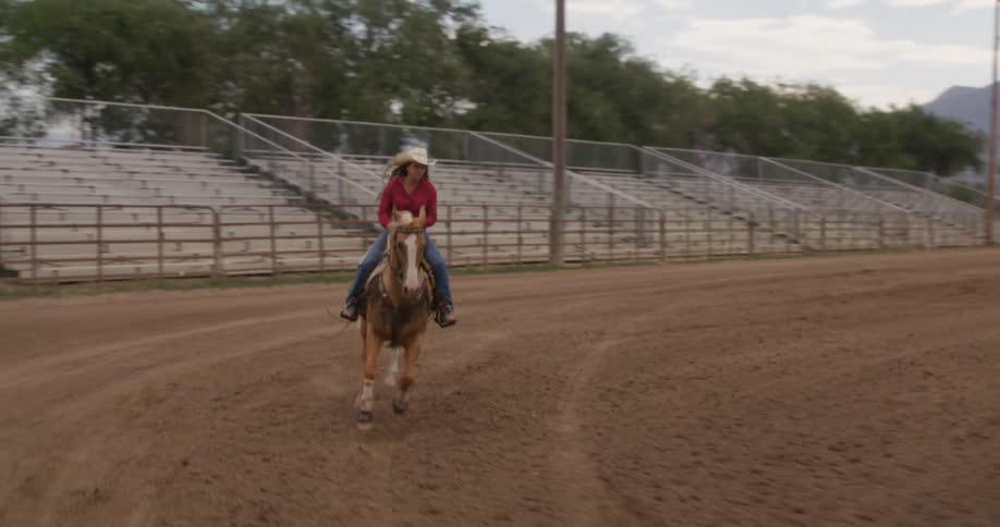 A woman is riding a horse in the rodeo arena
