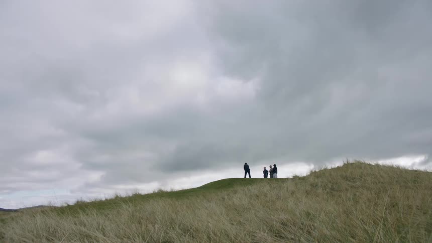 Four men golfing on a hill during the day