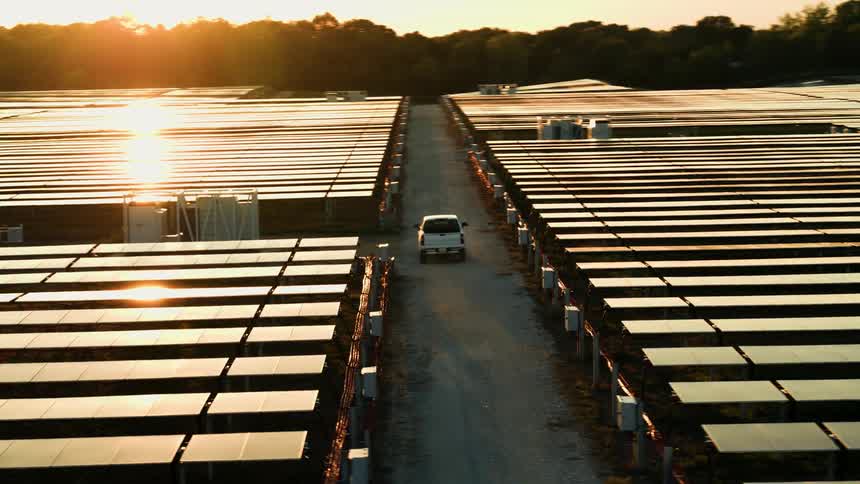 A pickup truck driving past a solar panel farm