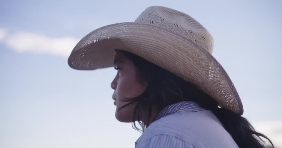 A young woman wearing a cowboy hat walking outdoors