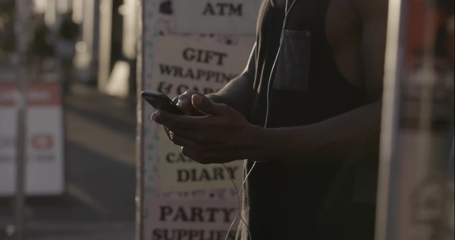A man is using his phone on a city sidewalk