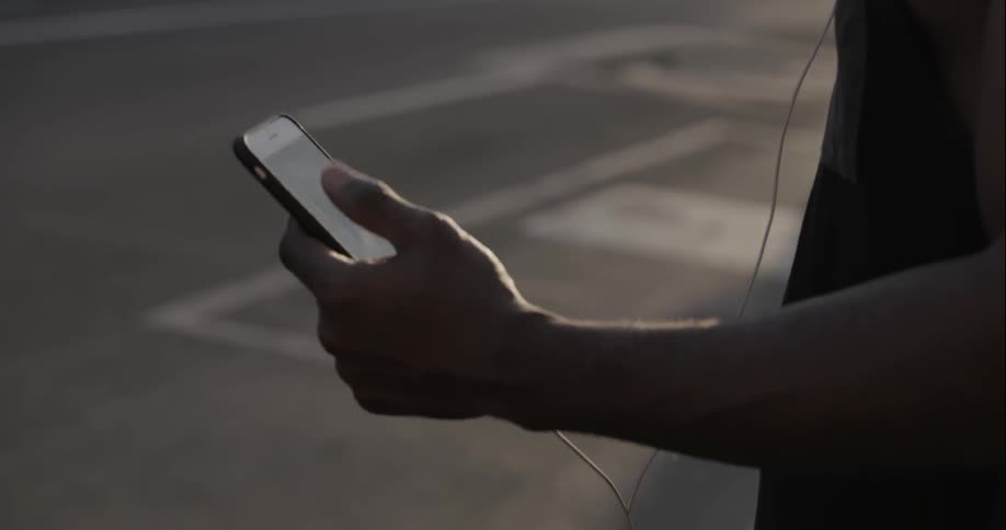 A man is using a phone standing by the street