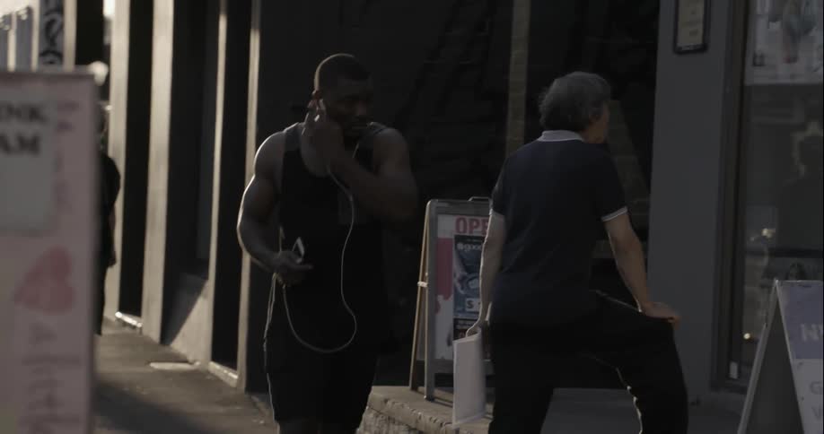 A man walks out of a building with other pedestrians walking past