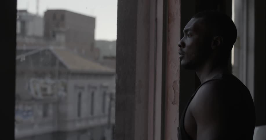 A man walks to a window overlooking a city