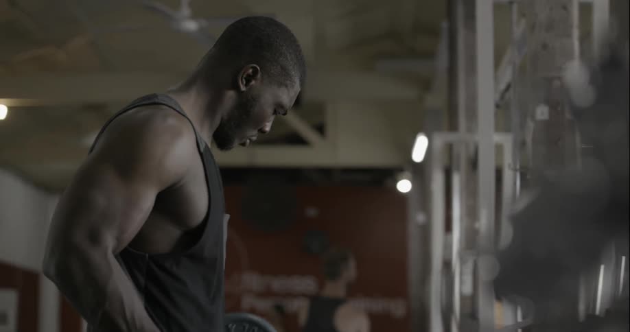 A man walks over to curl some weights