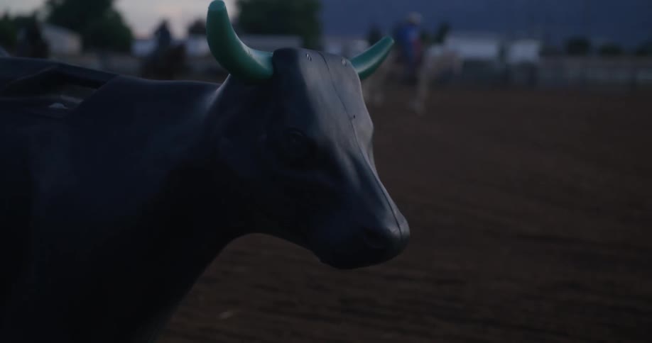 Two people ride past the bull device on horses