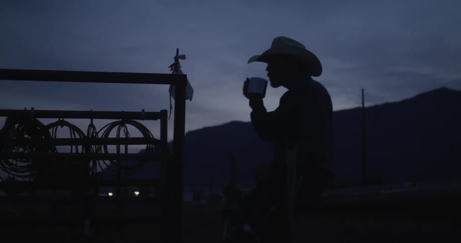 Cowboy drinking a cup in a dark early morning sky
