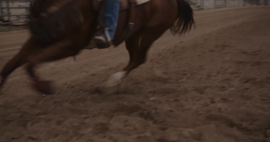 A lady rides a horse on a sandy field during the day