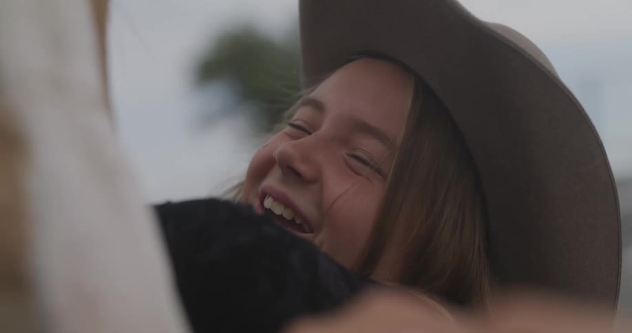 A kid wearing a hat playing with a horse
