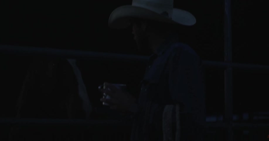 A clip of a man checking out a horse at the stable in the night