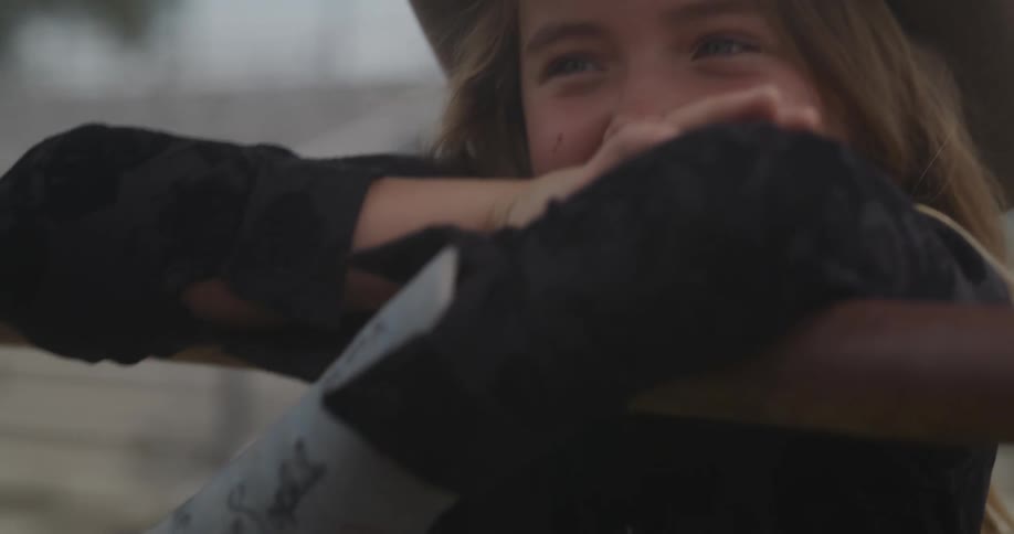 Girl with a cast and a cowboy hat smiles in a rodeo