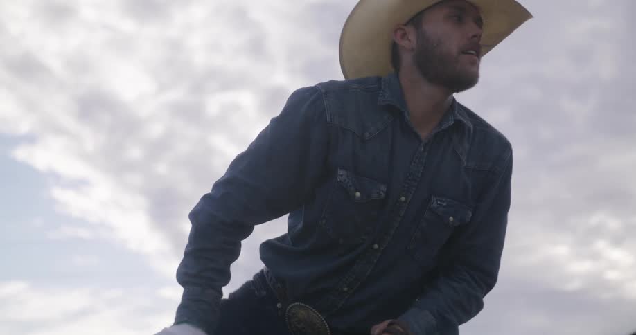 Cowboy climbs on a horse and rides away