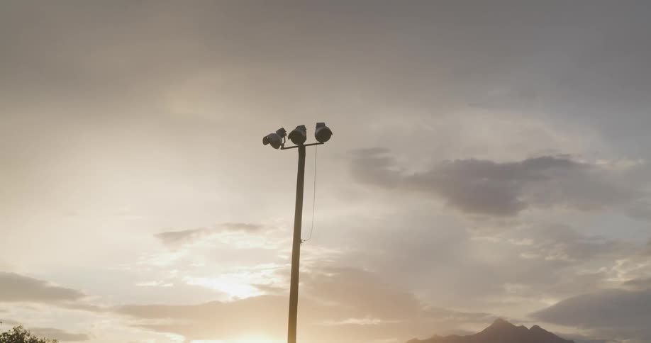 View of a light pole in a rodeo arena under a dark dawn sky