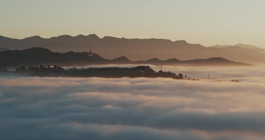 A thick layer of clouds in between a mountain range at sunrise