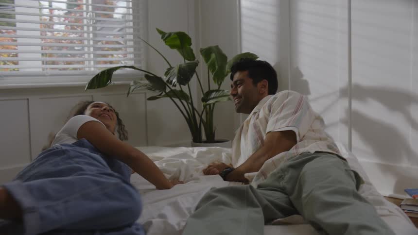 Man and woman jumps on the bed while talking and smiling