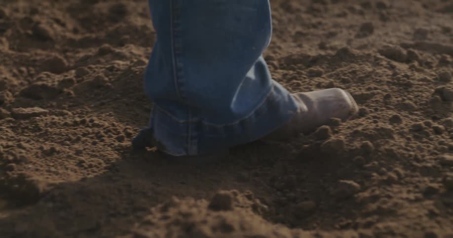 A person wearing boots is kicking dirt on a field