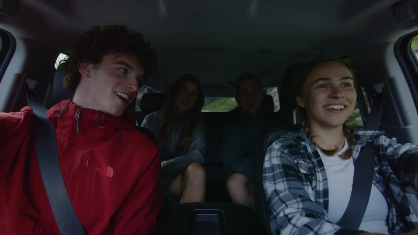 Four teenagers talk and laugh in a car