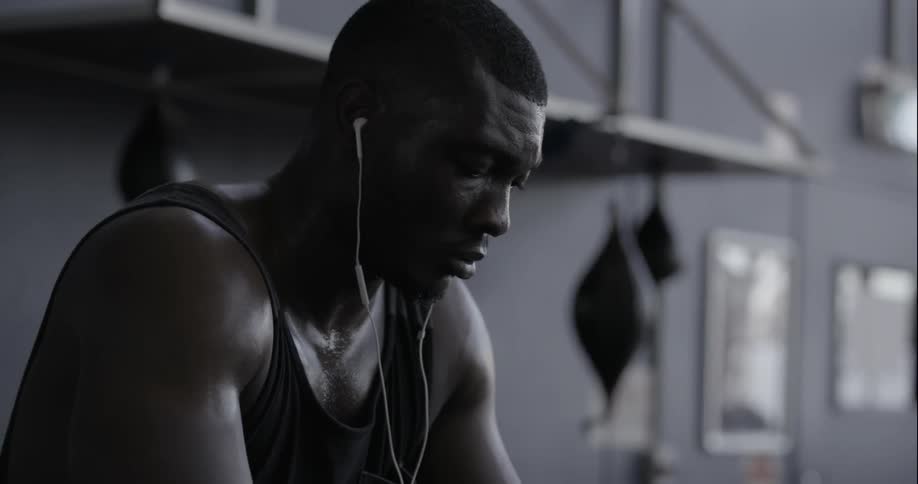 Man sitting in a locker room listening to his personal device