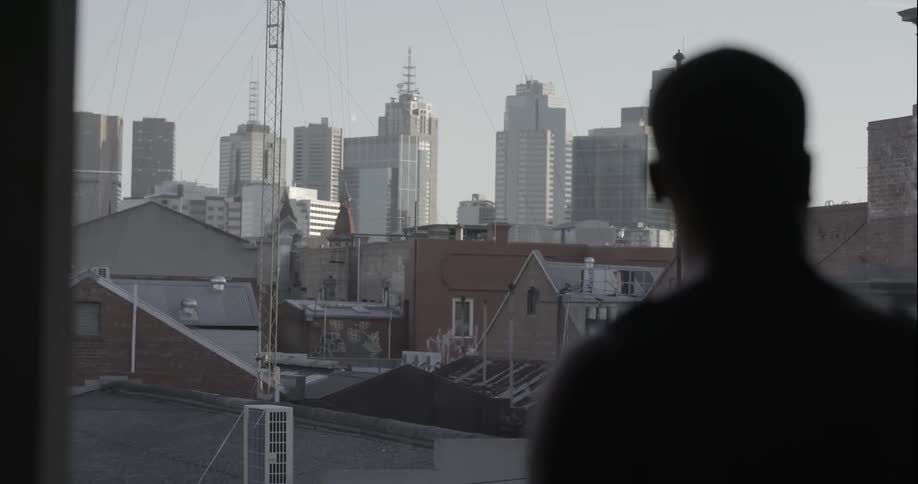 Man looking out a window seeing a large city