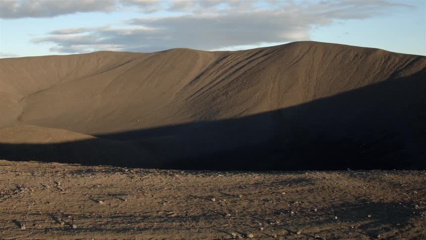 A desert leads to some tall sand dunes