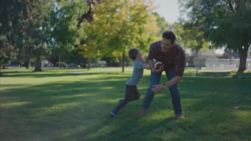 Father and son plays around in a park during the day