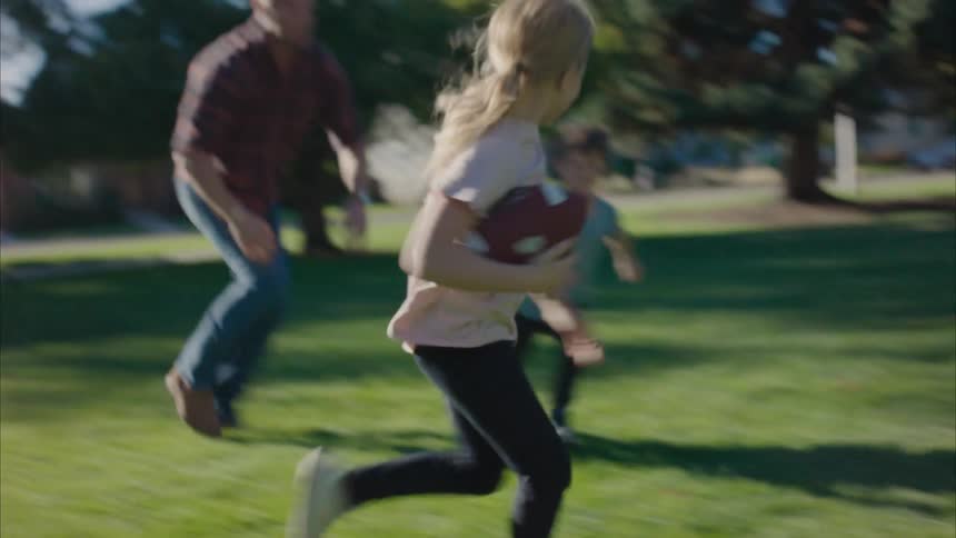 A father is playing football with his kids