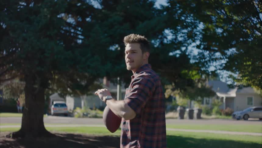 A man throwing a football and catching it on a sunny day outdoor