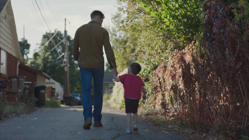 Father walking on the street hand in hand with his young son