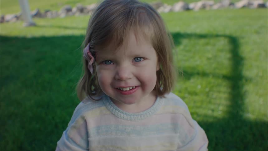 A kid smiling and playing to the camera