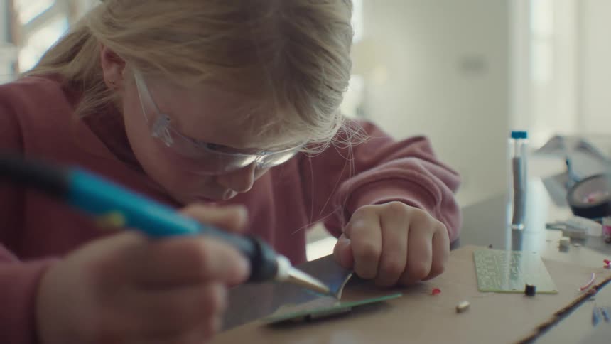 A child is soldering a computer chip