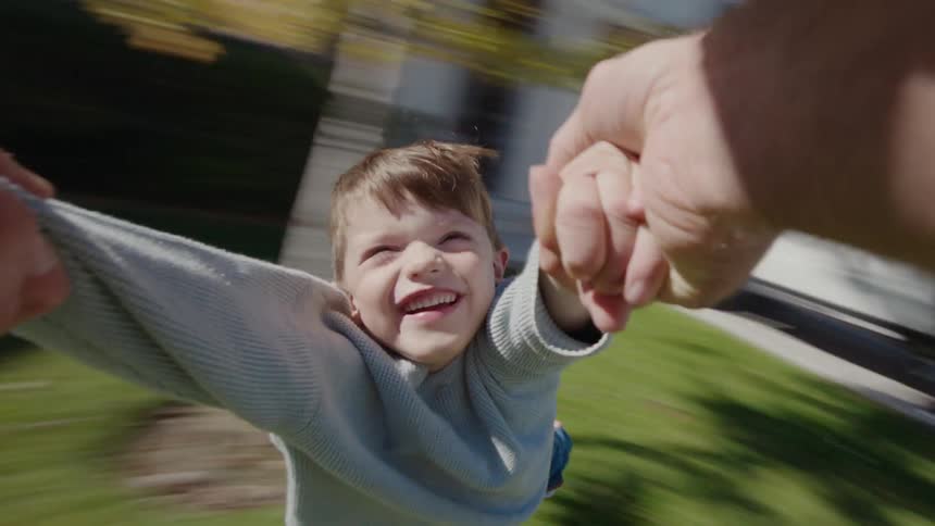 Father spinning his son in the yard
