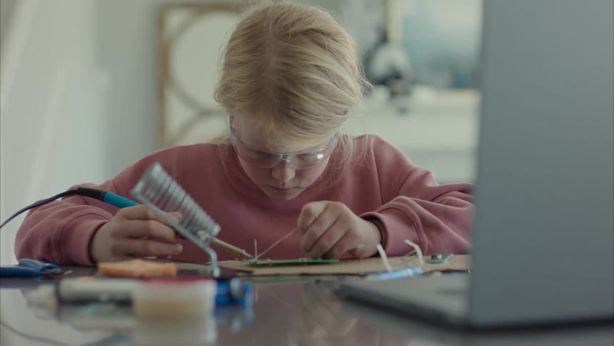 Girl wearing protective goggles working on electronics